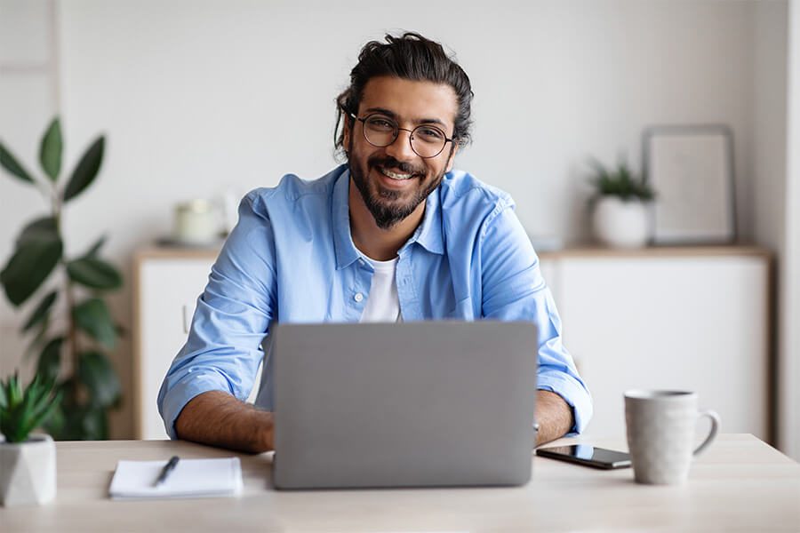 Male smiling whilst working on a laptop