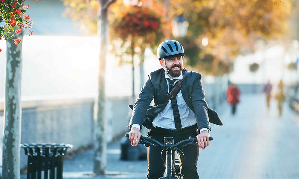 Man smiling while wearing a helmet and riding a bike